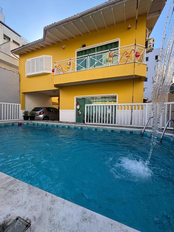 une maison avec une piscine devant une maison dans l'établissement SR Casa de férias Astúrias, à Guarujá