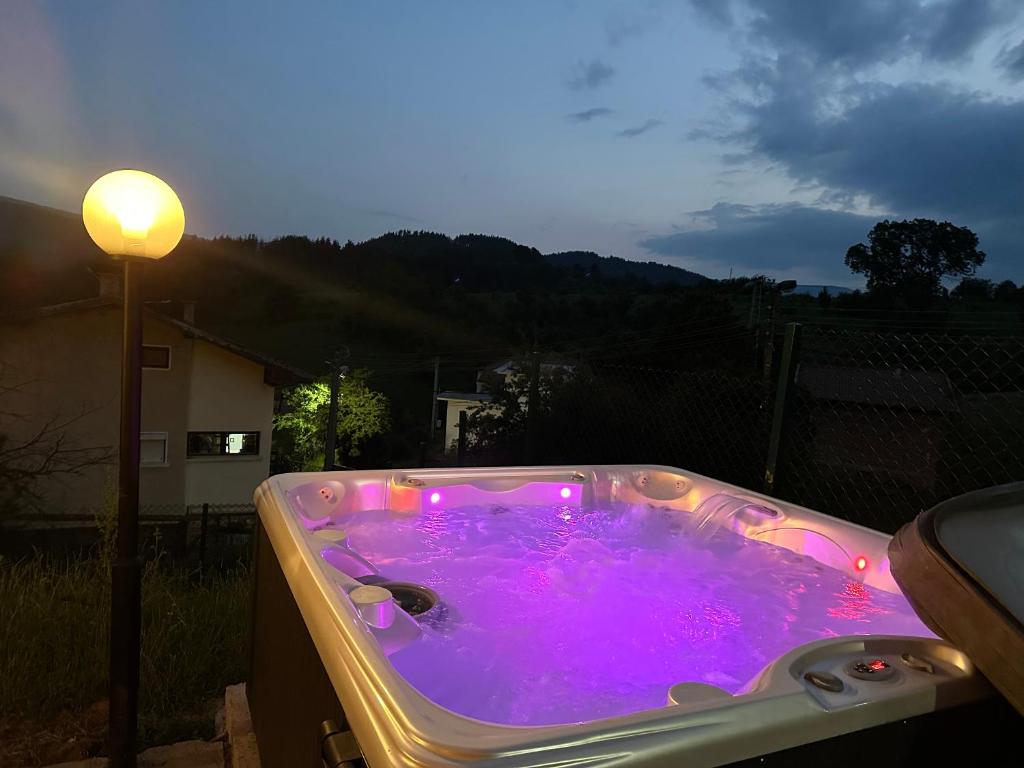 a jacuzzi tub with purple lights in a backyard at Къща за гости Sunrise - Батак in Batak
