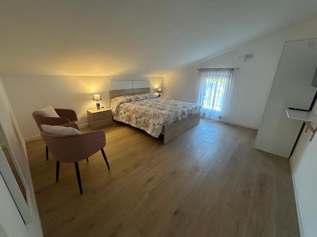 - une grande chambre avec un lit et une chaise dans l'établissement Home far from home, à Castelnuovo del Garda