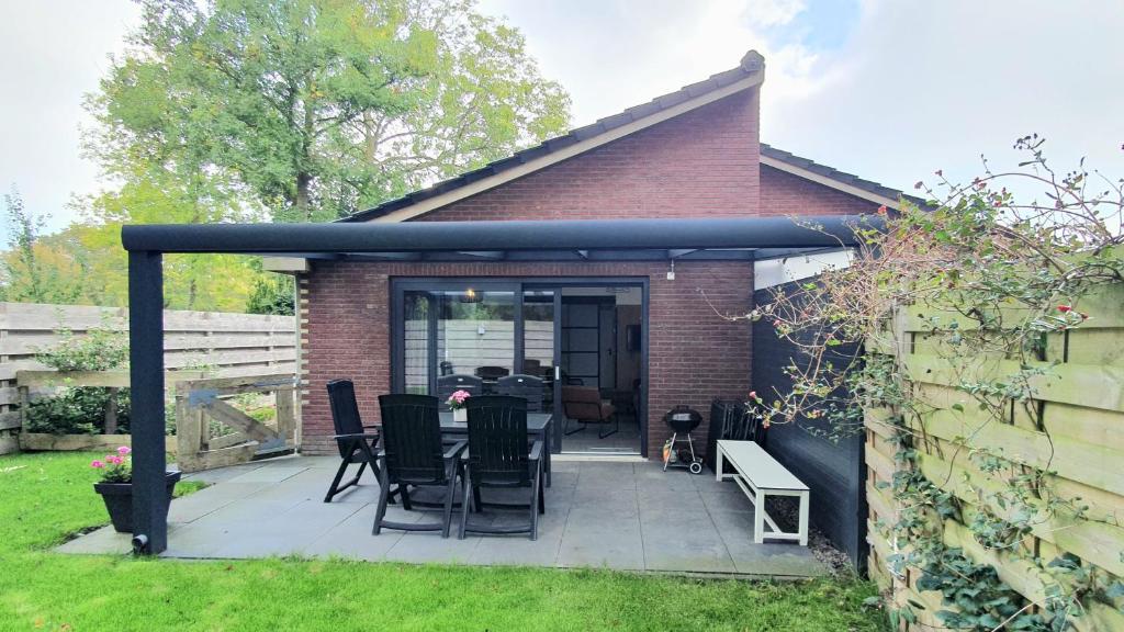 eine Terrasse mit Stühlen und einem Tisch im Hinterhof in der Unterkunft Luxe vakantiebungalow Rust, Ruimte en Privacy in Dirkshorn