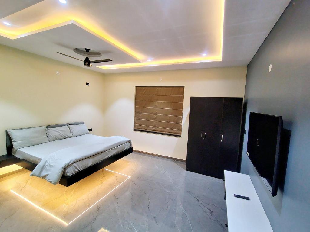 a bedroom with a bed and a flat screen tv at Luxe poolside farmhouse -J House in Hyderabad