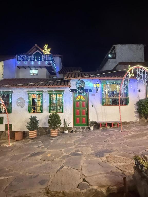a white building with a red door with christmas lights at Monguí Posada Familiar in Duitama