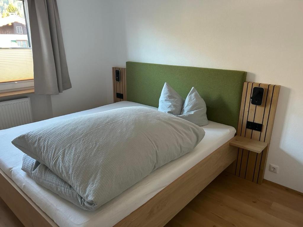 een bed met een groen hoofdeinde in een slaapkamer bij Schöne Aussicht in Riezlern