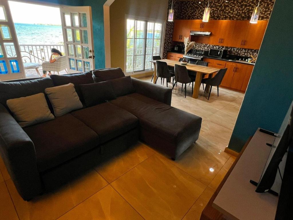 a living room with a brown couch and a kitchen at Casa Vista al Amatique in Puerto Barrios