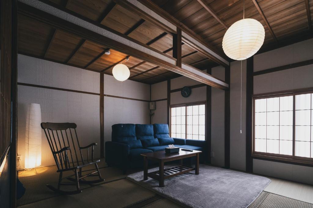 a living room with a blue couch and a table at Hidasumika Daimon Cozyan in Takayama