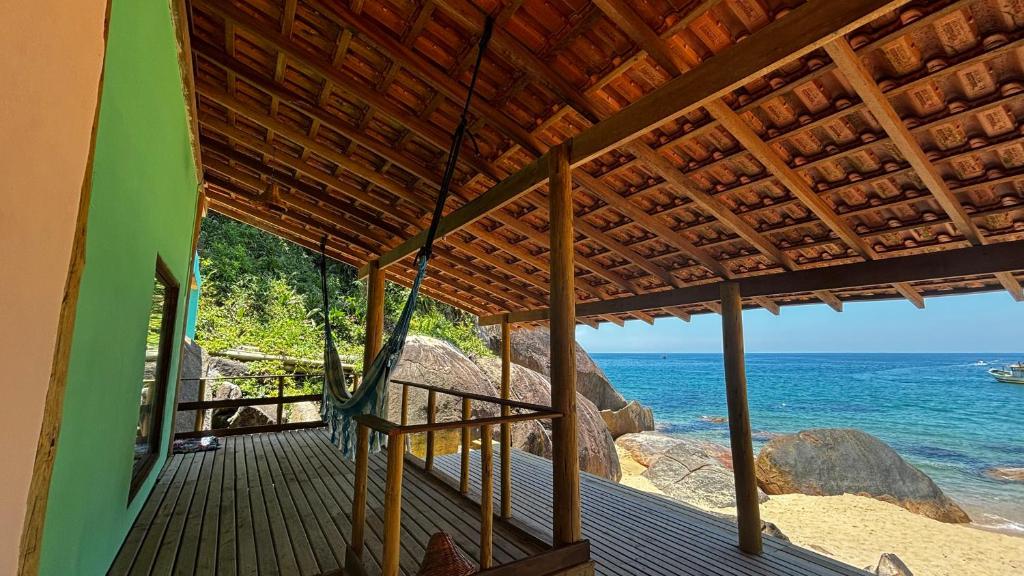 een uitzicht op het strand vanaf de veranda van een huis bij Chalé Pé na Areia Por do Sol in Paraty
