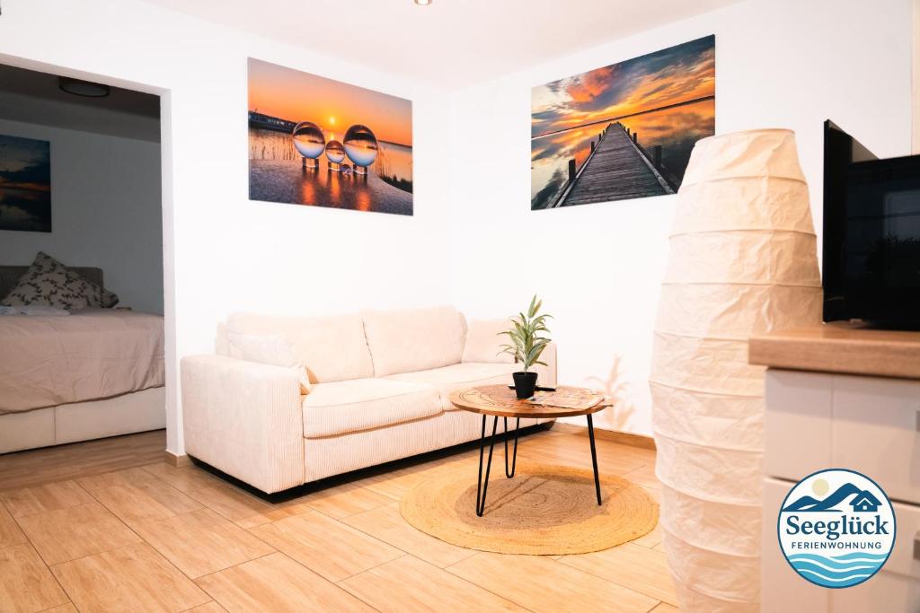 een woonkamer met een witte bank en een tafel bij Ferienwohnung See Glück in Wunstorf