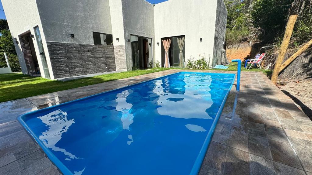una piscina blu davanti a una casa di Casa aconchego a Santa Cruz Cabrália