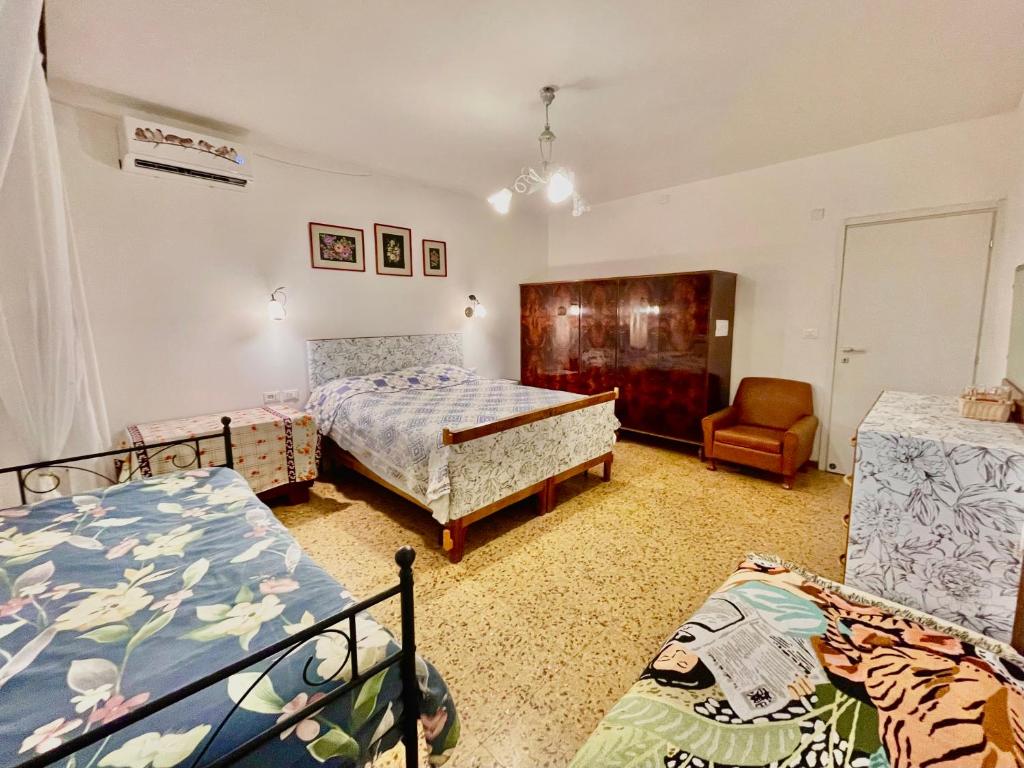 a bedroom with two beds and a chair at L'ENCANTO DE LUNA -Una Casa Autentica Comacchiese in Comacchio