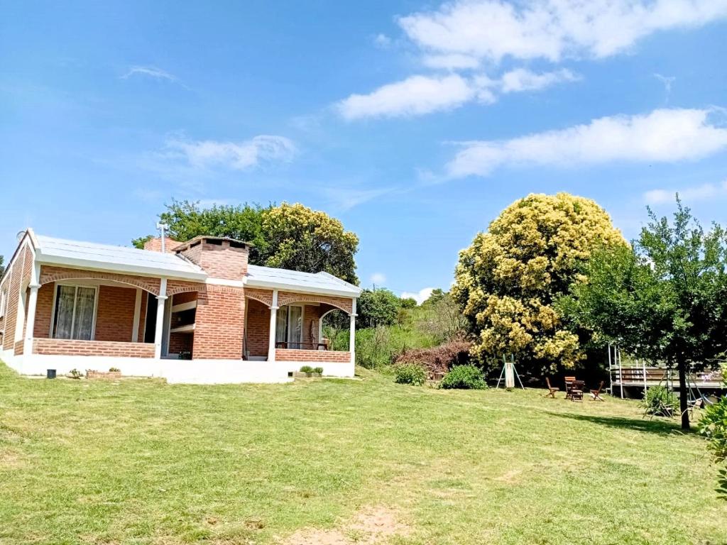 a house on a grassy field with a tree at Cabañas Las Pasionarias in Tanti
