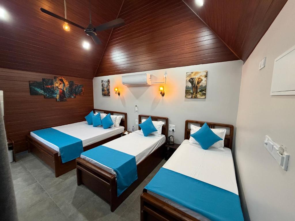 two beds in a room with wooden walls at Batti Lagoon Hotel in Batticaloa
