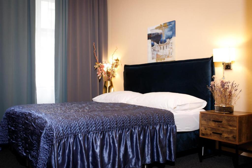 a bedroom with a large bed with a blue blanket at Hotel Bajazzo in Vienna