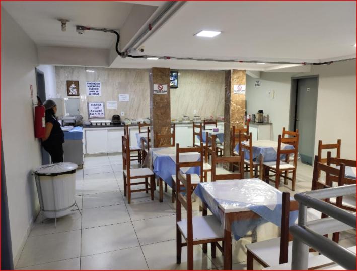 a restaurant with tables and chairs and a person in a kitchen at Estrela de davi in Goiânia