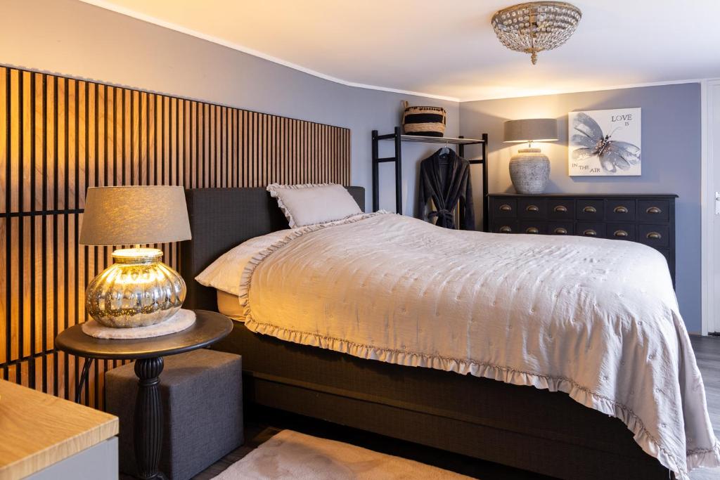 a bedroom with a bed and a table with a lamp at Het Woonrijk in Bennekom