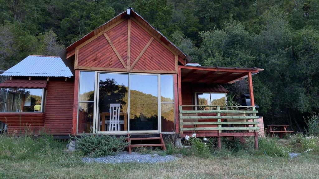 une petite maison rouge avec une grande fenêtre en verre dans l'établissement Cabañas Vega del Molino, à Linares