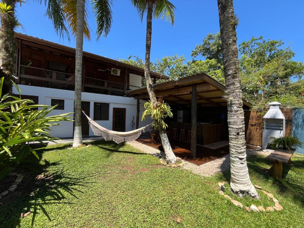 a hammock in front of a house with palm trees at Pousada Nalu - Camburi in Camburi