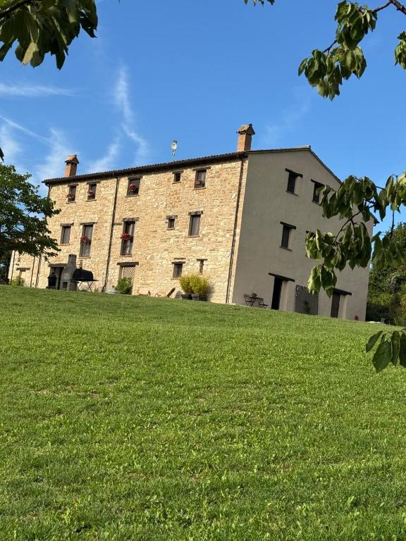 a large brick building on top of a green field at Casale le Fontanelle in Monte Grimano Terme