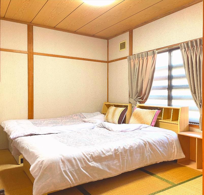 un grand lit dans une chambre avec une fenêtre dans l'établissement オイソ, à Iiyama