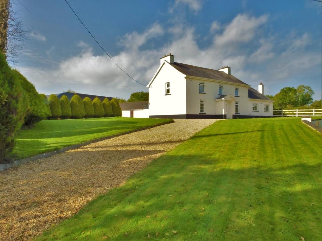 una casa blanca con un gran patio de césped en Belle View House Self Catering, en Mohill