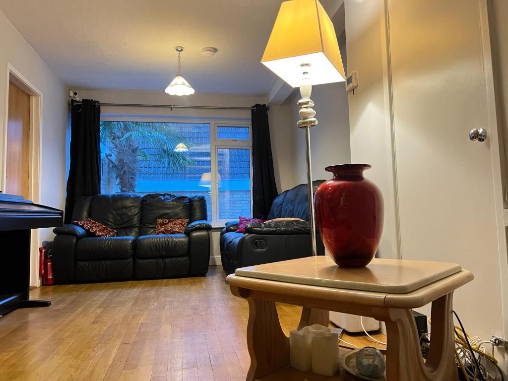 een woonkamer met een tafel met een lamp en een bank bij Zen suite in Oadby