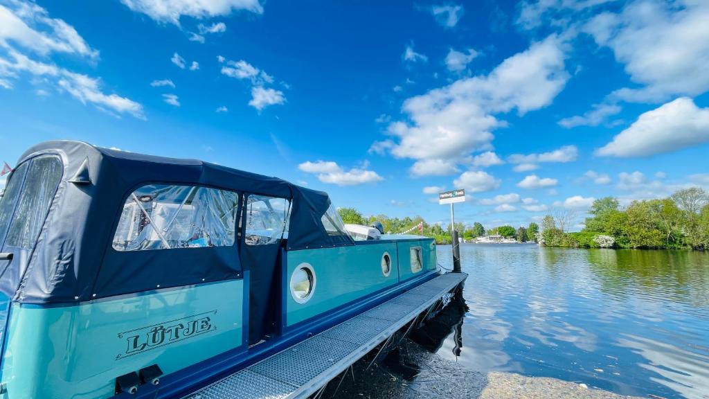 a blue boat parked at a dock on the water at Hausboot Lütje in Hamburg