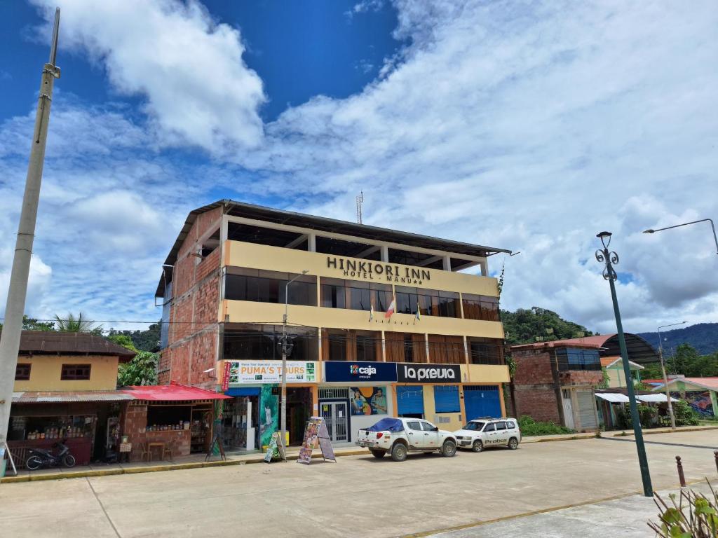 een gebouw met daarvoor geparkeerde auto's bij Hinkiori Inn - Hotel Manu in Pillcopata