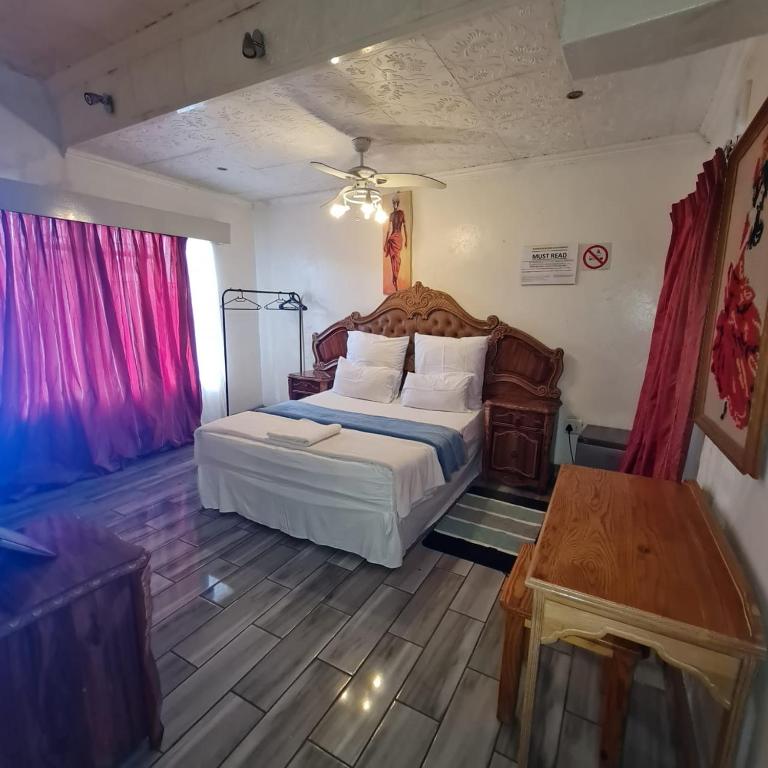 een slaapkamer met een groot bed en een tafel bij HostHub Guest House in Rustenburg