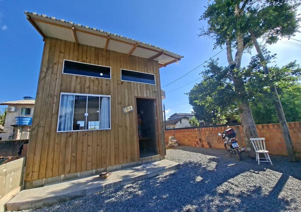 a wooden house with a tree in front of it at Mini Casa Mezanino in São Francisco do Sul