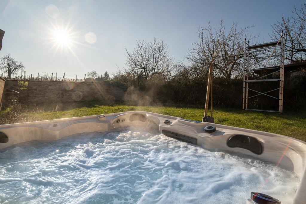 a hot tub in a yard with the sun in the background at The Gingerbread Spa - Private Parking - Terrace in Gertwiller