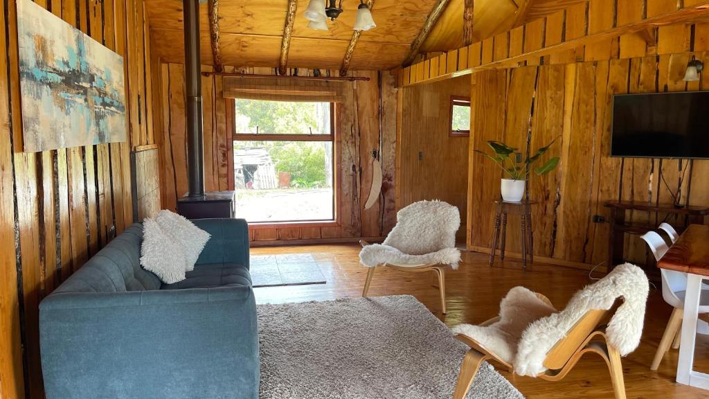 een woonkamer met een blauwe bank en een televisie bij Cabañas Kuela in Puerto Varas