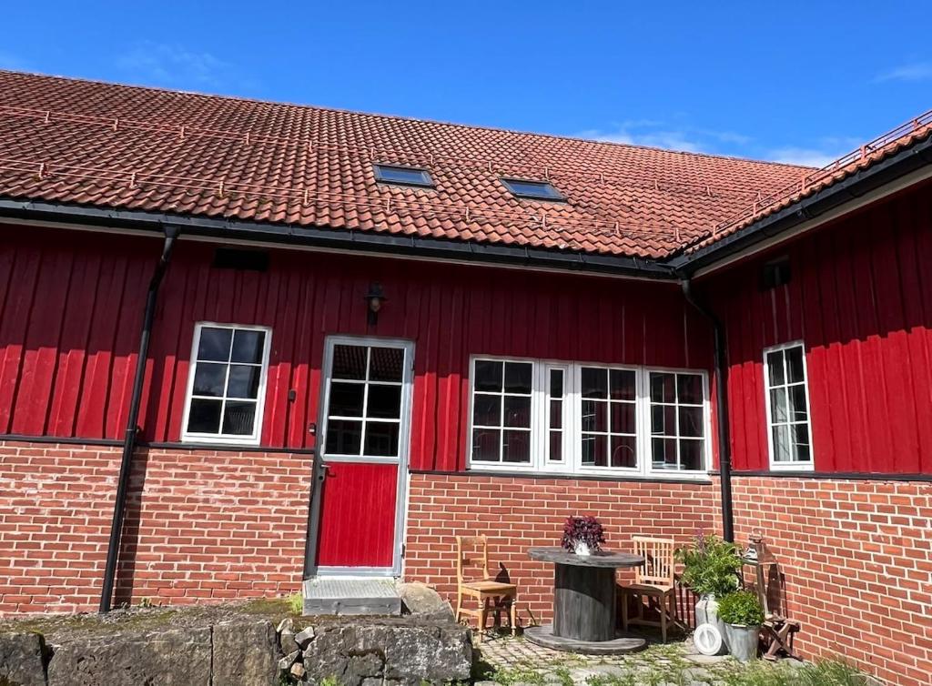 a red brick house with red doors and a table at Leilighet i låve in Gran