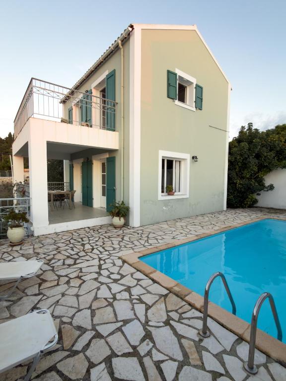 a villa with a swimming pool in front of a house at Regina Villa in Fiskardo