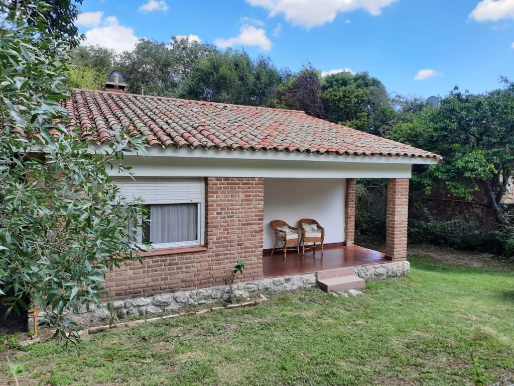a small brick house with two chairs in a yard at Casa de la Bove in La Cumbre