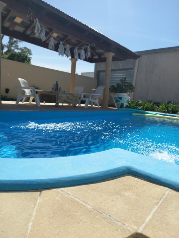 einen blauen Pool mit einem Tisch und Stühlen in der Unterkunft Condominio El Monte departamentos deluxe in San Nicolás de los Arroyos
