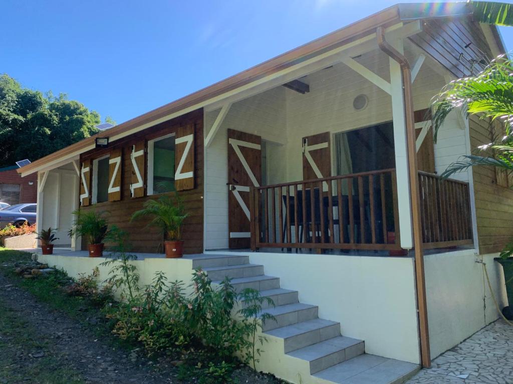 a house with a porch and stairs in front of it at BRADA gites in Deshaies