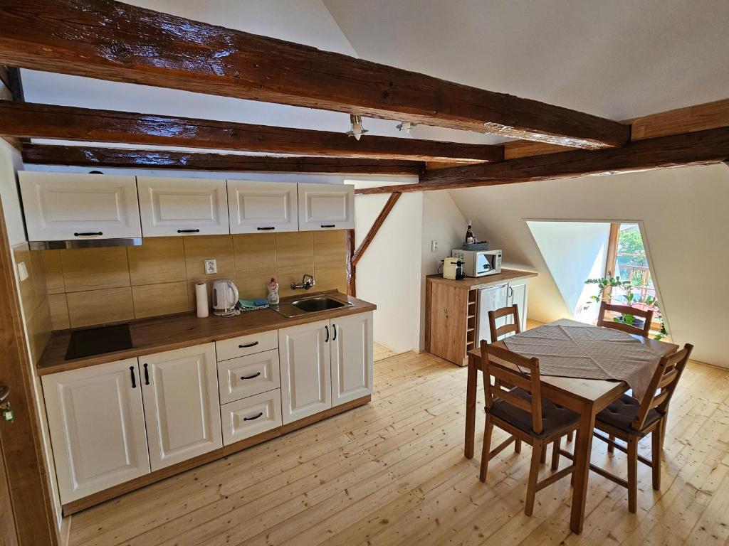 a kitchen with white cabinets and a table and a dining room at Apartmány Krásné zátiší in Krásno