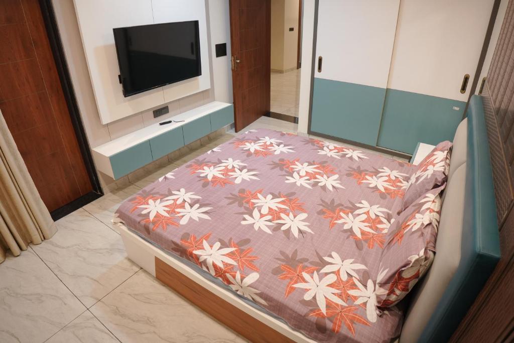 a bed in a room with a tv in a room at Apna Ghar in Jaipur