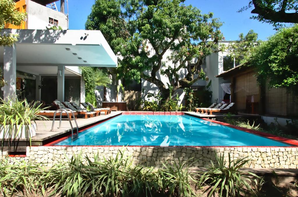 a swimming pool in a yard with chairs at Villa dos Graffitis Pousada in Morro de São Paulo