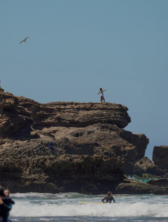 Eine Person, die auf einem Felsen im Meer steht in der Unterkunft Berber vibes in Tamraght Ouzdar