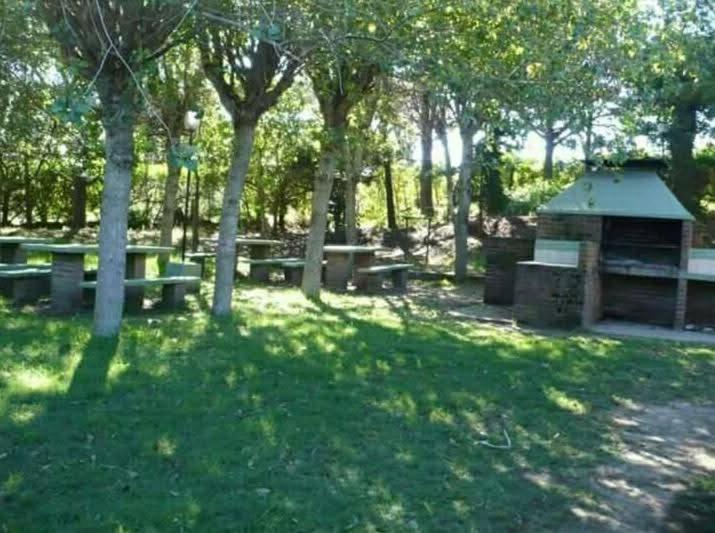 a group of picnic tables in a park with trees at Valeria del Mar Apartment in Valeria del Mar