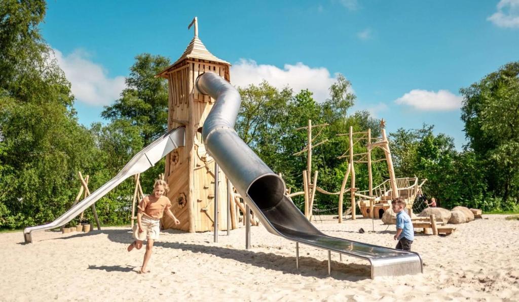 twee kinderen spelen op een glijbaan in een speeltuin bij Stacaravan Camping It Wiid Earnewoude in Earnewâld