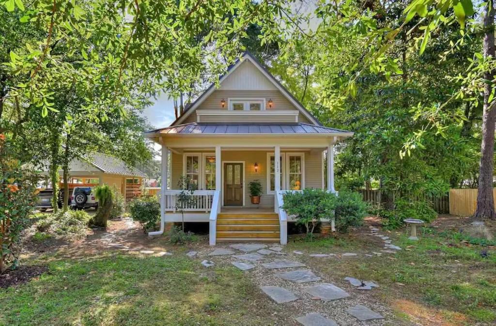 a small yellow house with a porch and stairs at The Owl Cottage in Aiken