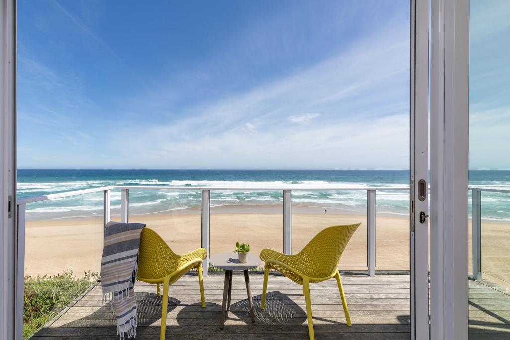 2 Stühle und ein Tisch auf dem Balkon mit Blick auf den Strand in der Unterkunft Dune Beach House in Wilderness