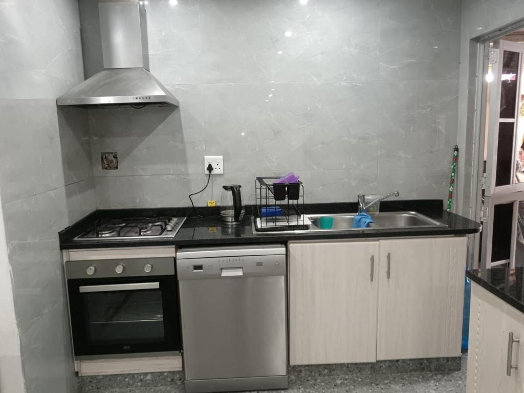 een keuken met een fornuis en een spoelbak bij Protea Place Cottage in La Mercy