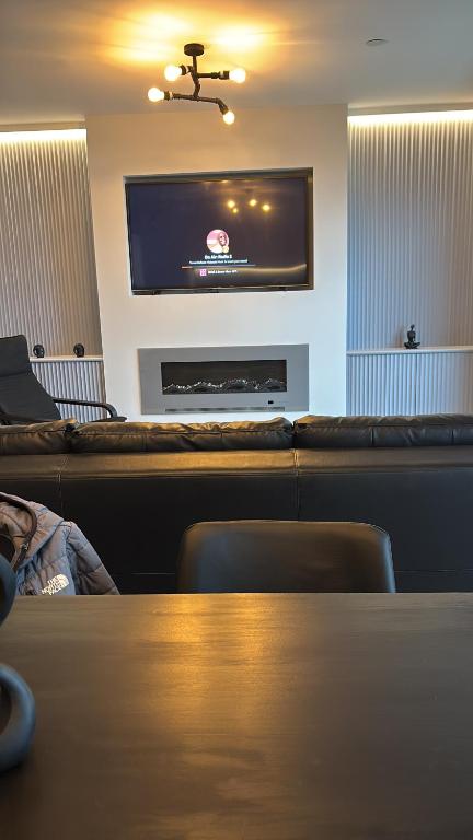 a living room with a table and a flat screen tv at The New 2 Plas Morolwg in Aberystwyth