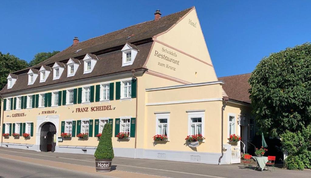 ein gelbes Gebäude mit grünen Fensterläden an einer Straße in der Unterkunft Hotel Scheidels Kranz in Kenzingen