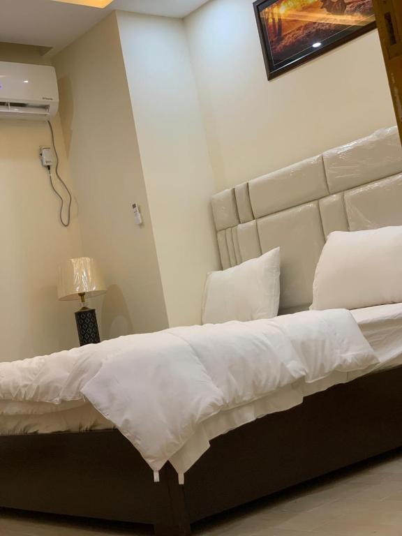 a bedroom with a large bed with white sheets and pillows at Pavilion 99 Serenity Appartment 2bhk in Rawalpindi
