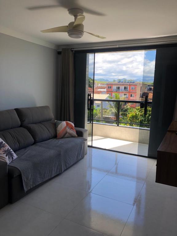 een woonkamer met een bank en een groot raam bij Apartamento Piúma in Piúma