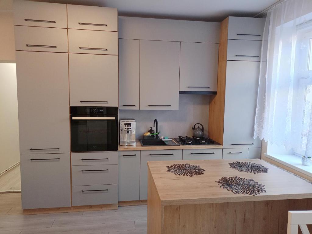 una cucina con mobili bianchi e un piano di lavoro in legno di Apartament BLISKO SZLAKU a Boguszów-Gorce