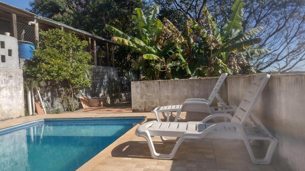 une paire de chaises et une piscine dans l'établissement CHÁCARA dos CHEIROS, à Atibaia